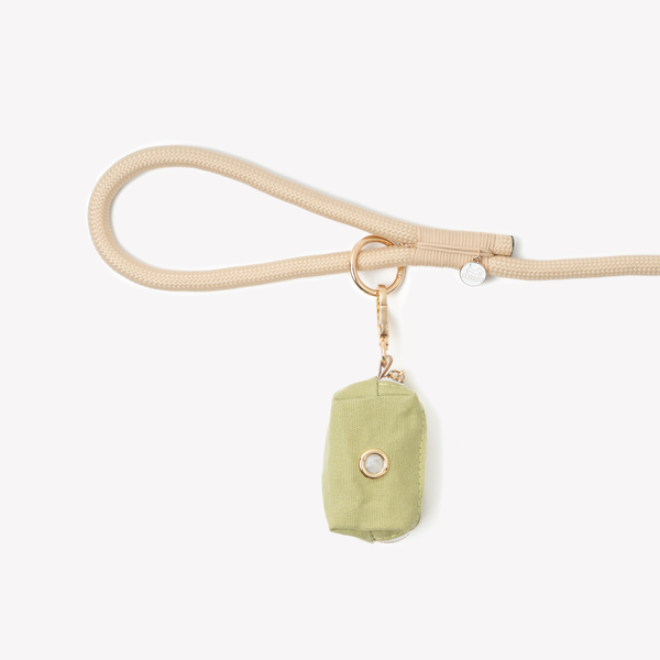 Green poop bag holder clipped to a leash handle