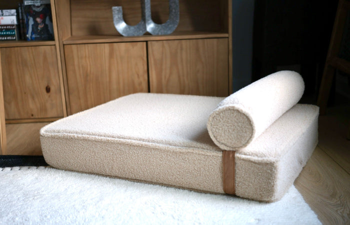 Modern Day boucle dog bed with its bolster on a white rug