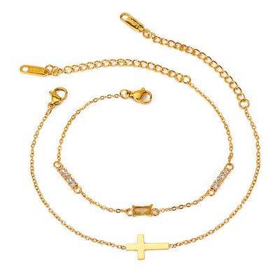 Gold tone bracelet set, 18K gold plated, with two fine cable chains featuring a cross charm and a slim bar with clear crystal accents, lobster clasps and extender chains visible.