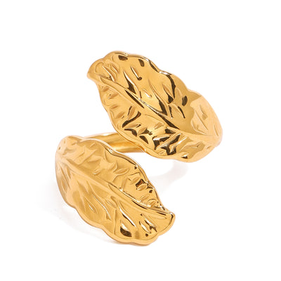 Gold tone cuff ring, 18K gold plated, with two leaf-shaped ends featuring veined textured detailing and a mirror high-polish finish, open cuff construction, no stones visible.