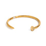 Gold tone cuff bracelet, 18K gold plated, in a nail-inspired open design with a smooth rounded band and tiny clear pavé crystal accents on the head and along the band, no other stones visible.