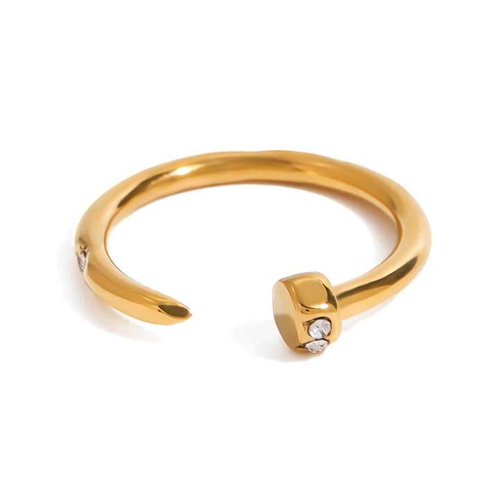 Gold tone cuff ring, 18K gold plated, in a nail-inspired open design with a smooth rounded band and a geometric head set with tiny clear pavé crystal accents, no other stones visible.